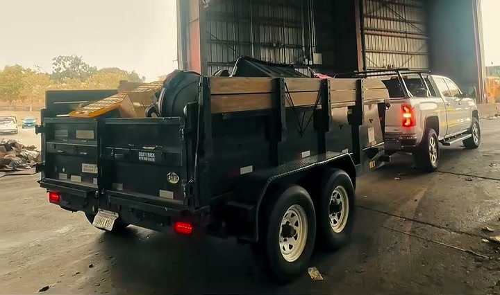 The bin trailer loaded with household items, parked beside the pickup
